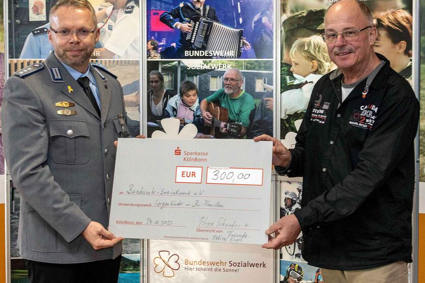 Erlös der Spendenaktion „Engel“: Oberstabsfeldwebel a.D. Hans-Dieter Schander übergibt einen symbolischen Spendenscheck über 300 Euro an Hauptmann Sigge.