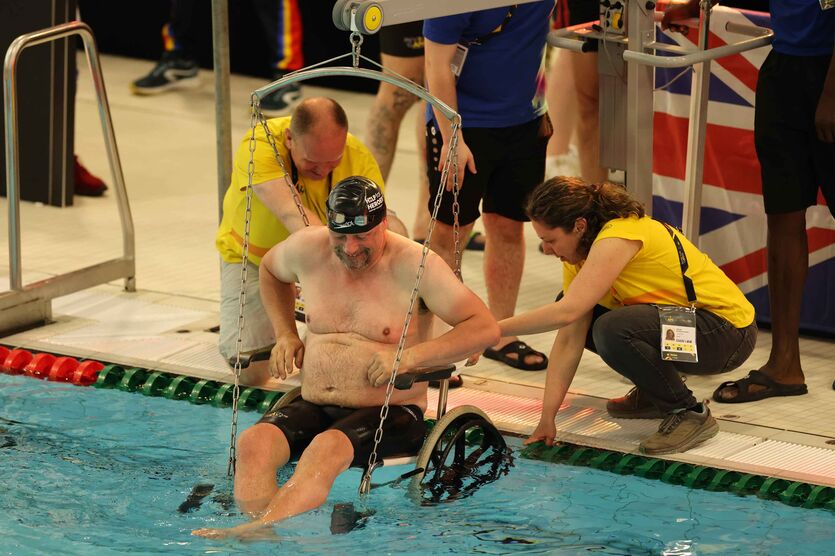 Die Volunteers bei den Schwimmwettkämpfen helfen den Rollstuhlfahrern mithilfe eines Liftes ins Wasser. 