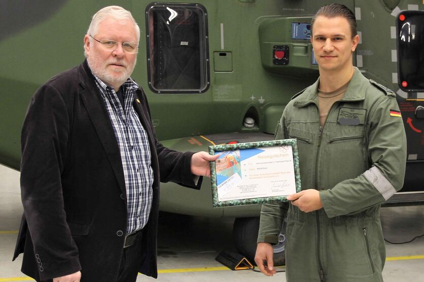 Oberstleutnant a.D. Martin Heuwinkel (li.) überreicht Hauptfeldwebel Florian K. den Hauptpreis der Weihnachtstombola, einen Reisegutschein des BwSW. 