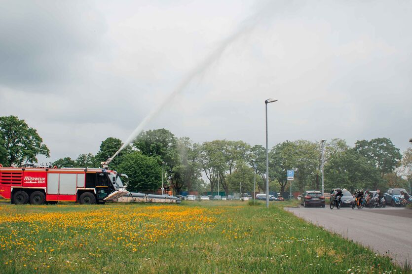 Begrüßung mit einer kühlenden Wasserfontäne der Bundeswehr-Feuerwehr: Zieleinfahrt der Spendenradtour 2023 in Köln-Wahn