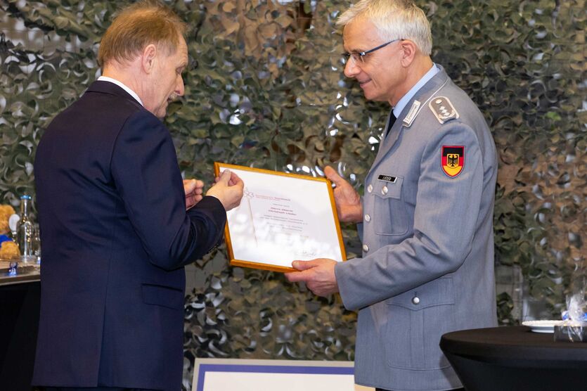 Schwarz auf Weiß: Oberst Christoph Lieder nimmt vom Bundesvorsitzenden Peter Dormanns die Urkunde zur Auszeichnung mit der Ehrennadel des Bundeswehr-Sozialwerks in Gold entgegen. 